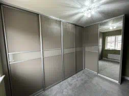 Stone grey wooden panels with a small stone grey glass dividing bar in an L shaped wardrobes, fitted in Middlesbrough